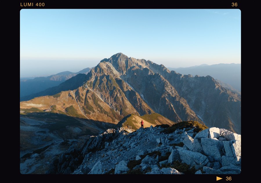 横幅远山样片：暖光照亮山坡，登山者站在远处